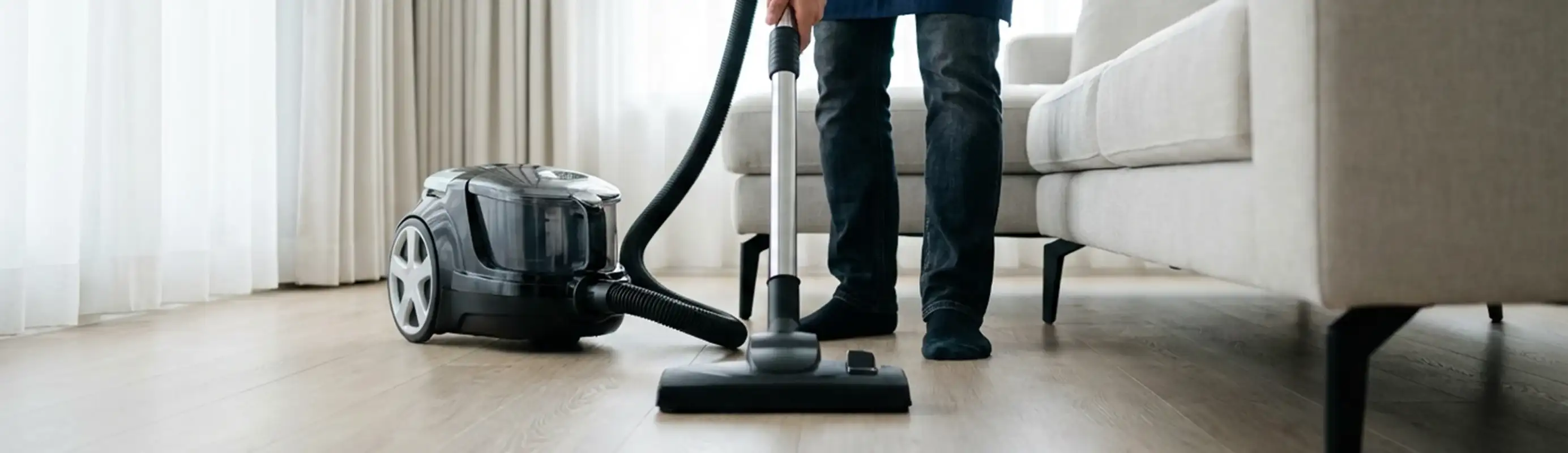 Professional house cleaner vacuuming a living room floor with a canister vacuum cleaner, Scottsdale, AZ.