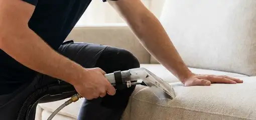 Professional upholstery cleaner deep-cleaning a fabric sofa with a handheld extraction tool, Scottsdale, AZ.